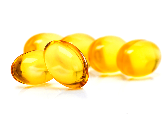 Golden capsules of Vitamin E on a white background